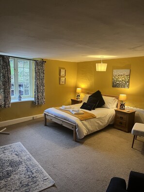 A bedroom with a bed, bedside tables, a lamp, a chair, and a window with curtains. - The Who'd Have Thought It Inn (Yelverton)