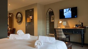 Een hotelkamer met een bed, bureau, stoel, televisie en spiegel.