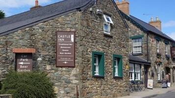 Un edificio in pietra con un cartello che indica Castle Inn, che offre un bar tradizionale, un ristorante, camere e un birrificio all'aperto.