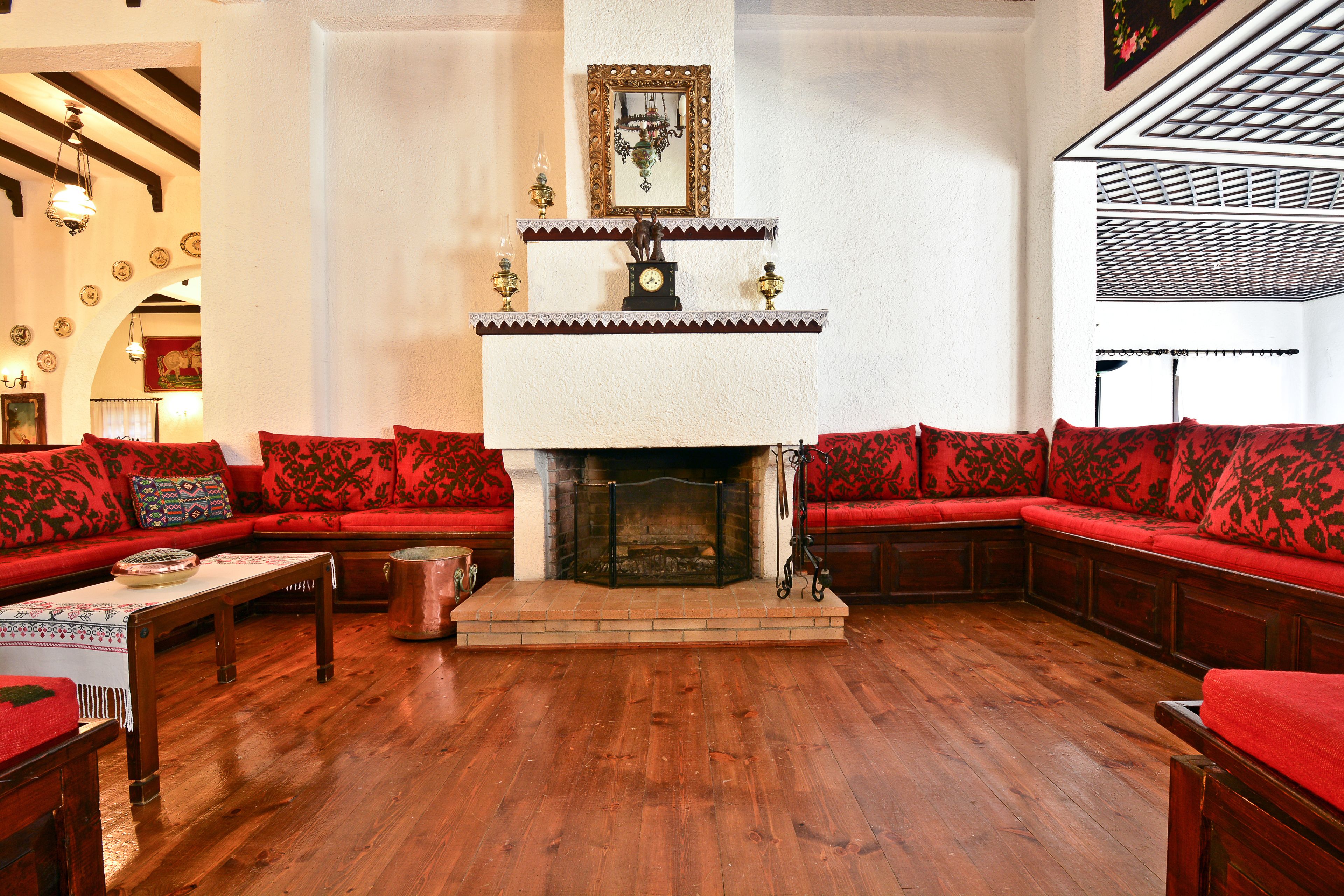 A cozy living room with a fireplace, red upholstered seating, and wooden flooring.