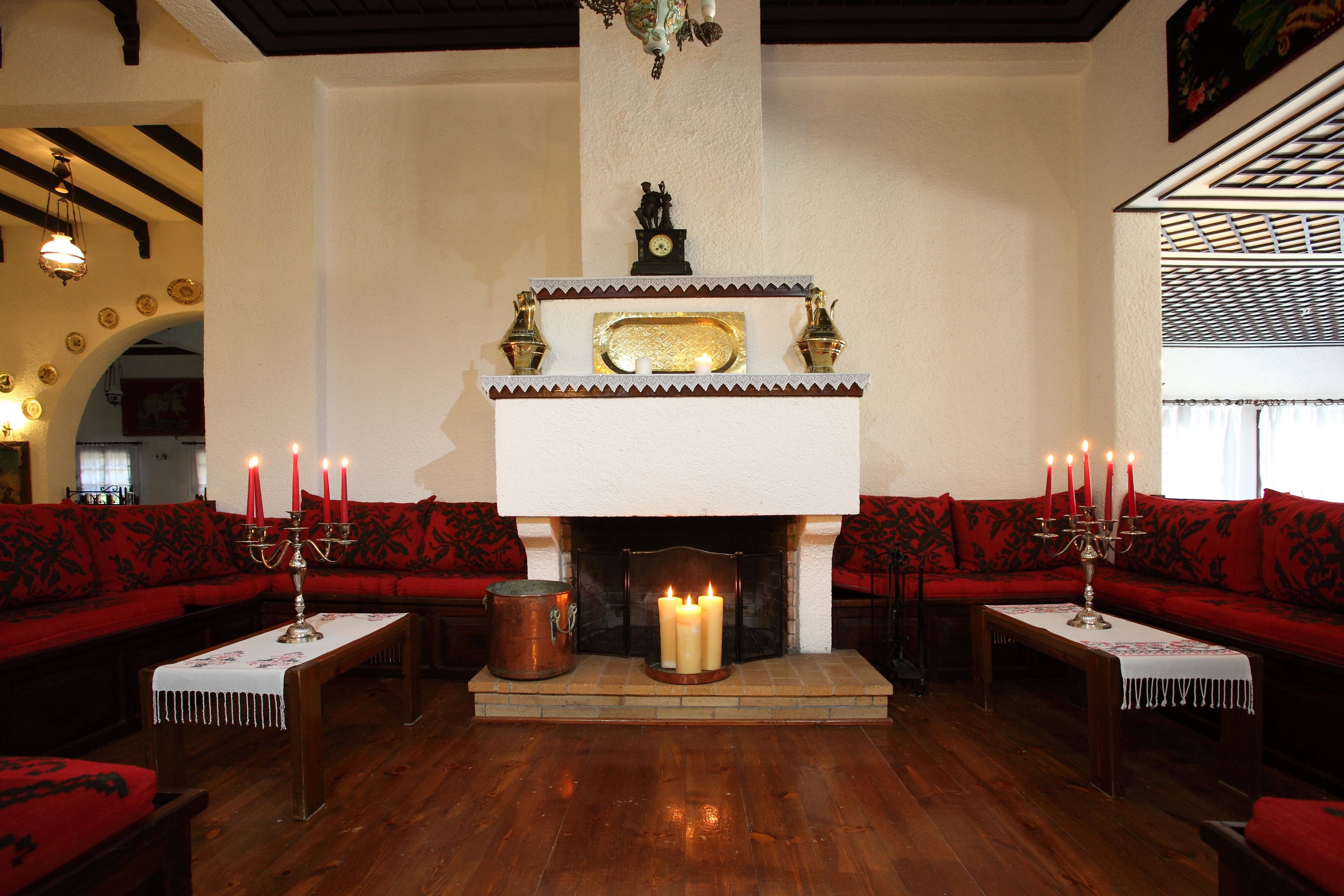 A cozy living room with a fireplace, red upholstered sofas, and a wooden floor.