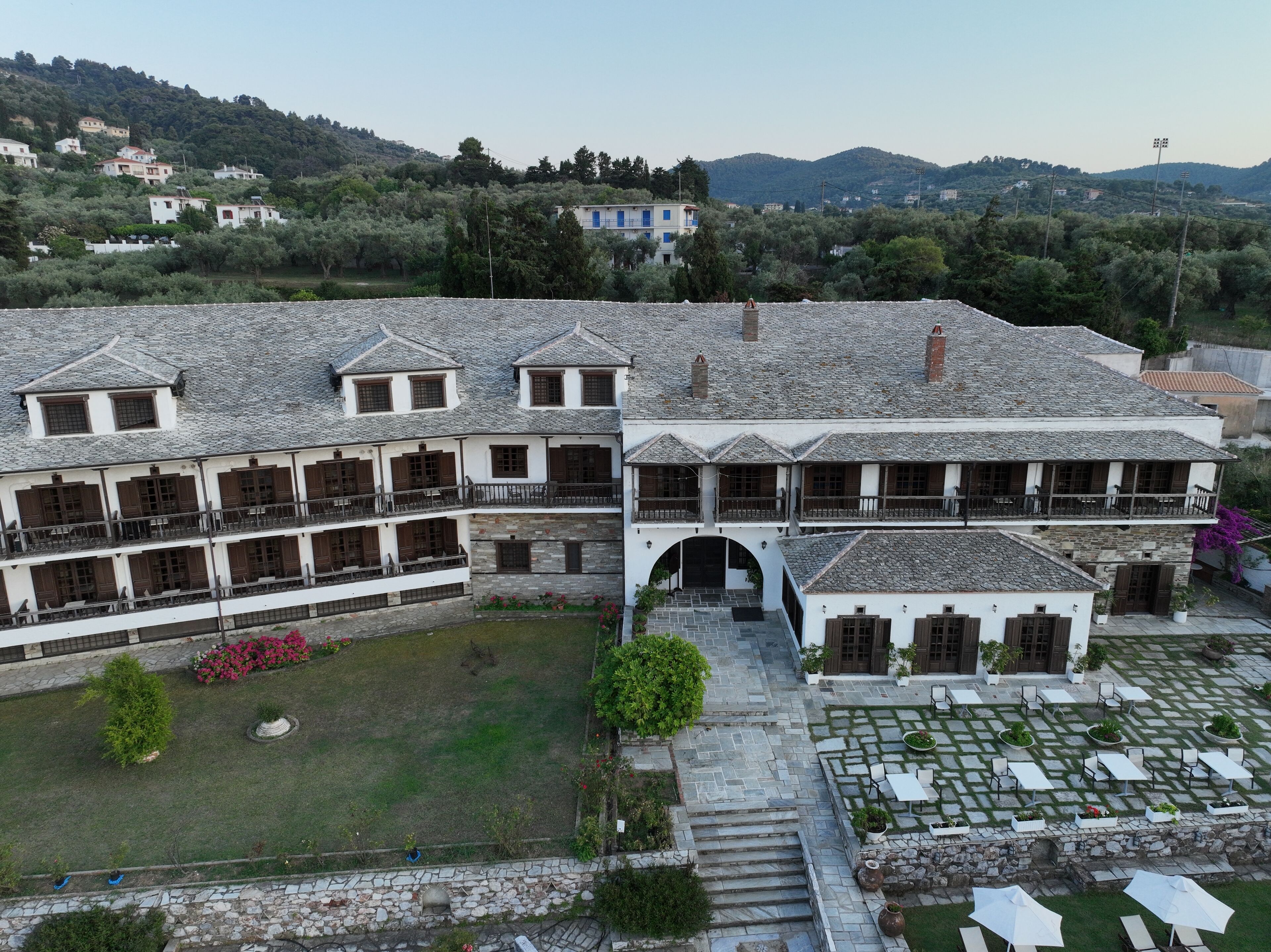Un edificio tradicional con varios balcones, un patio con asientos y vistas del paisaje circundante.