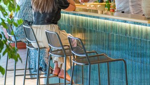 A bar area with a counter, bar stools, and a person serving a drink. - Hotel Villa Ireos (Ischia)