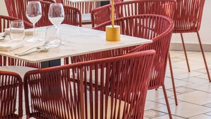 A dining area with red wicker chairs and a table set for two, overlooking a scenic view of the sea. - Hotel Villa Ireos (Ischia)