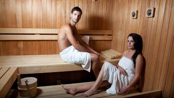 A sauna with wooden benches, a wooden bucket, and a wall-mounted clock.