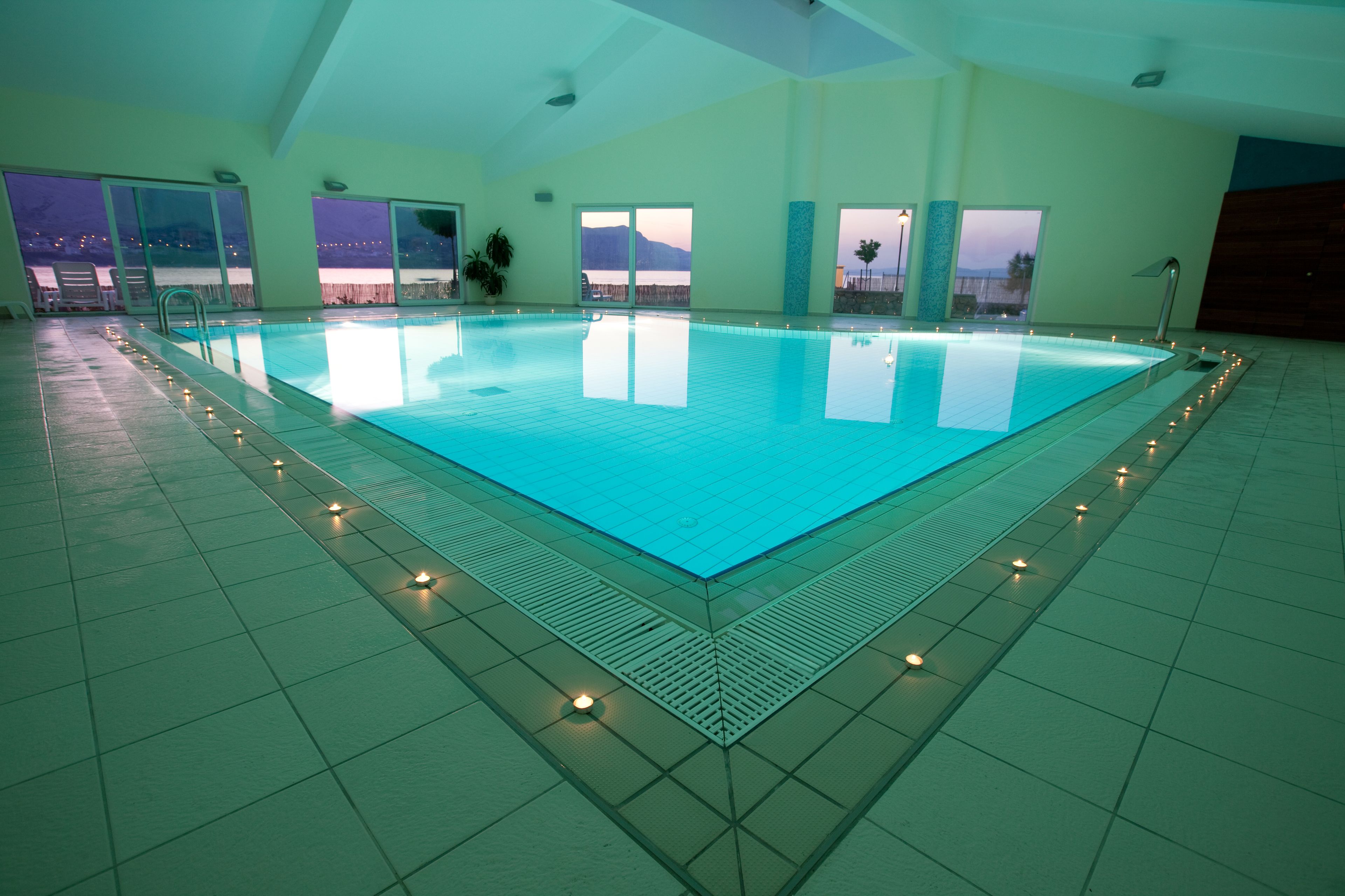 An indoor swimming pool with a view of the mountains through large windows.
