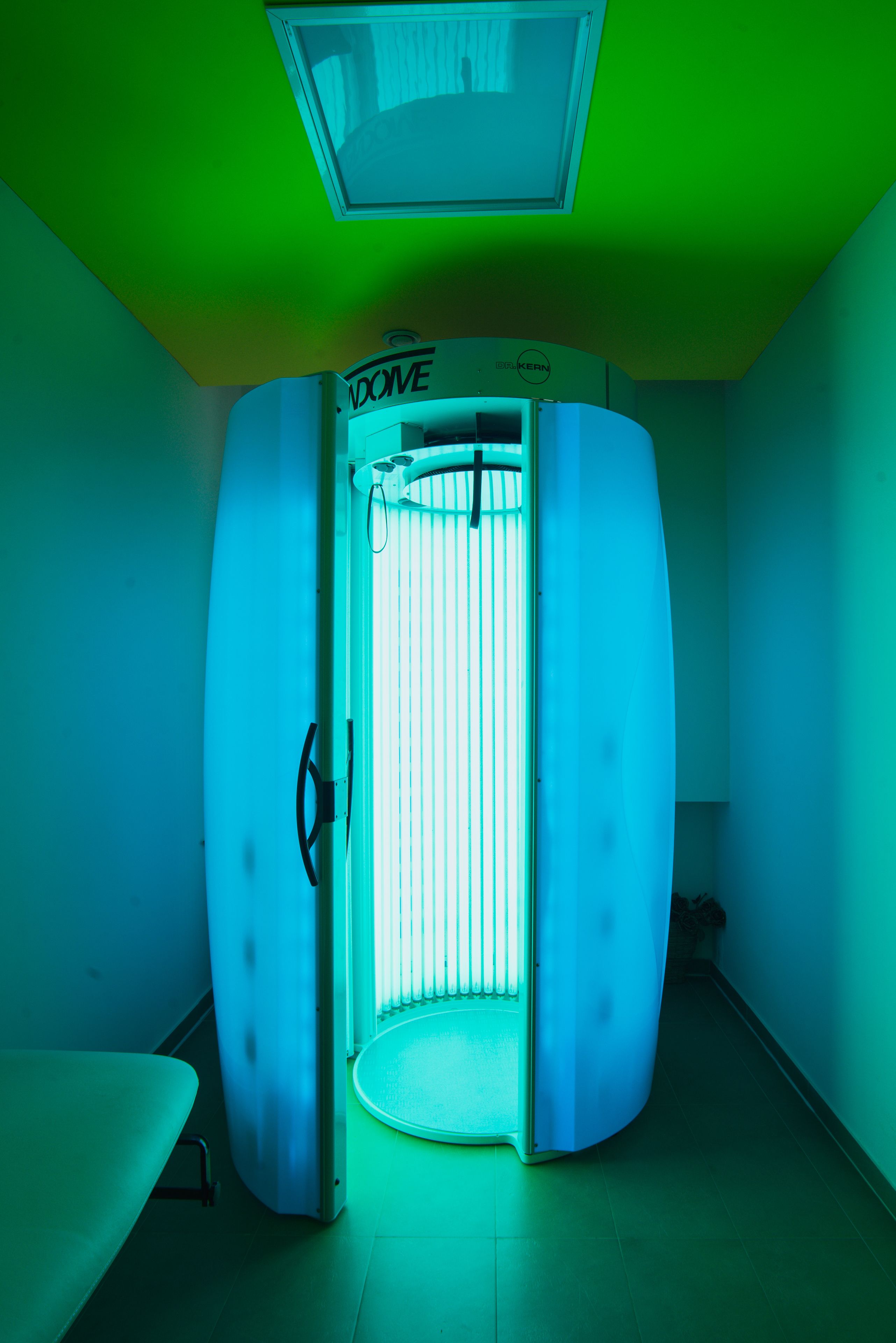Et rum med en stor, buet, hvid konstruktion med en dør, muligvis en sauna eller behandlingsrum, samt en lampe i loftet.
