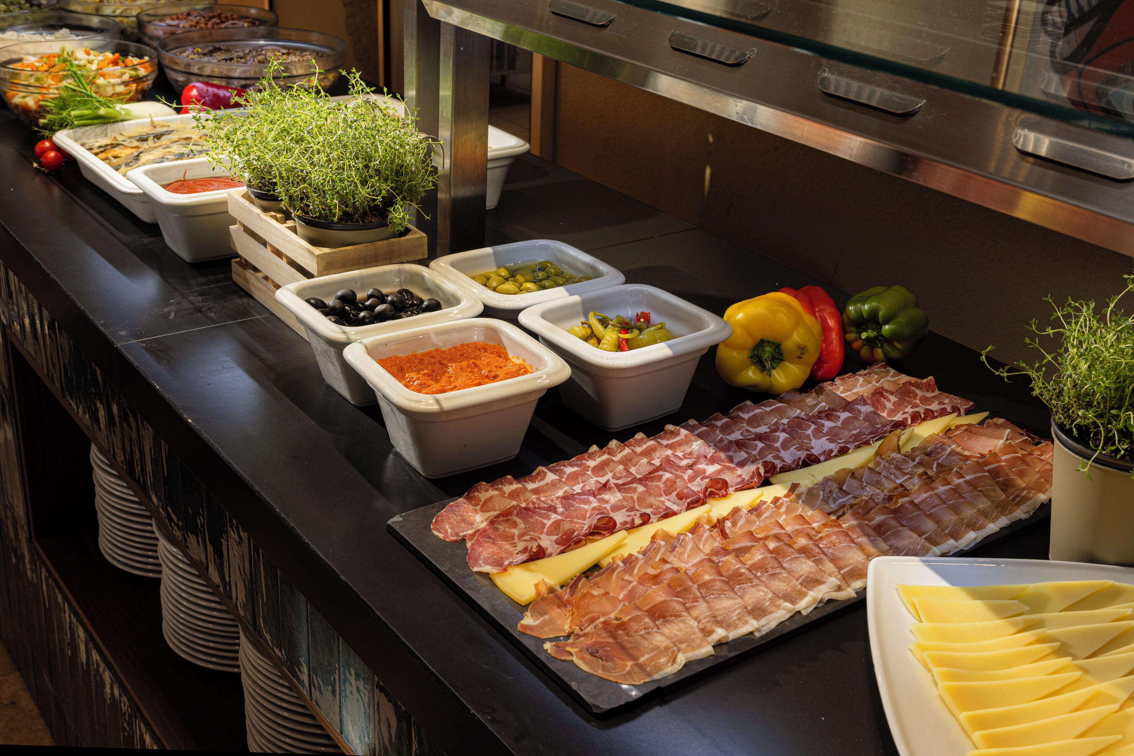 A buffet with various food items including meats, cheeses, and vegetables.