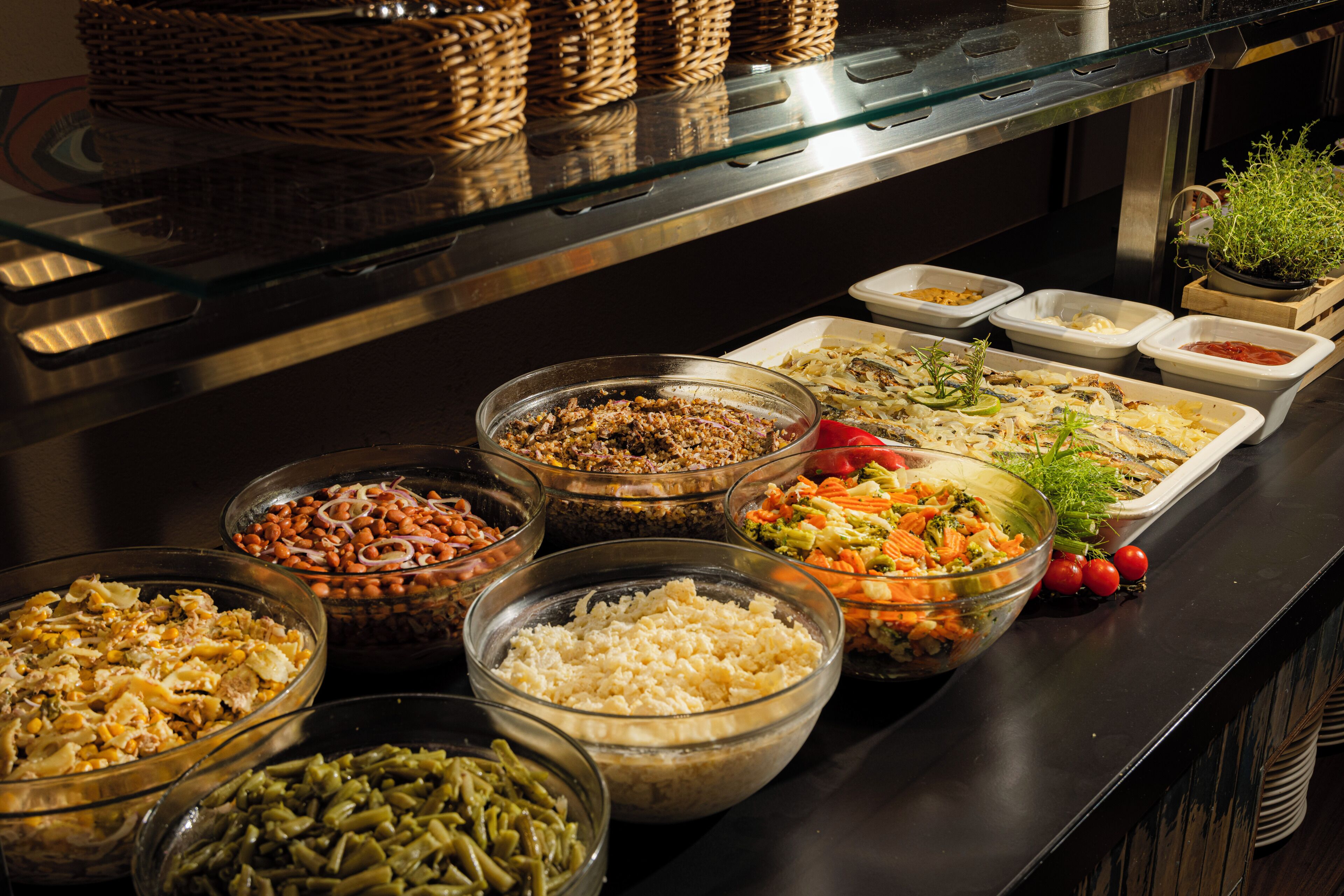 A buffet with various food options including salads, rice, and beans.