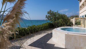 Piscina com vista para o mar, rodeada por vegetação e um caminho de pedras.