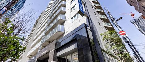 Un edificio moderno de gran altura con una fachada de vidrio destacada, múltiples balcones y un letrero visible que indica un hotel.