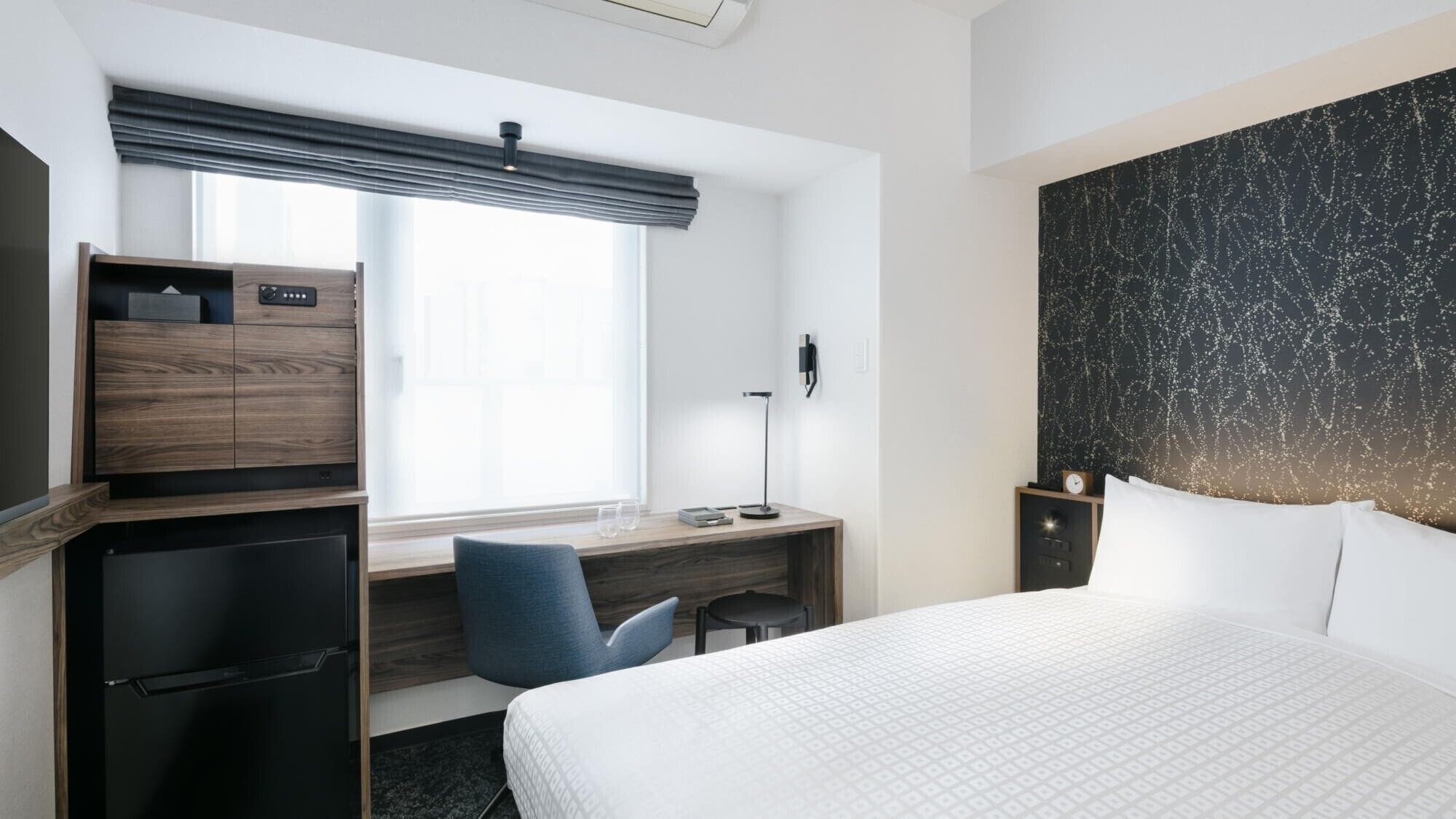 Una camera d'albergo con un letto, una scrivania, una sedia e un armadio.