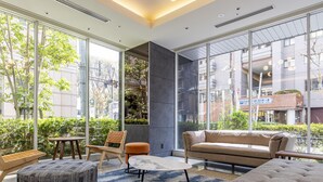 Un intérieur moderne avec de grandes fenêtres, un canapé, des poufs et une petite table.