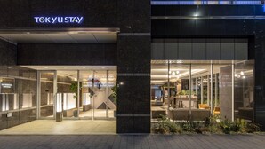 L’entrée moderne de l’hôtel se distingue par sa façade en verre, son espace d’accueil et son coin salon extérieur.