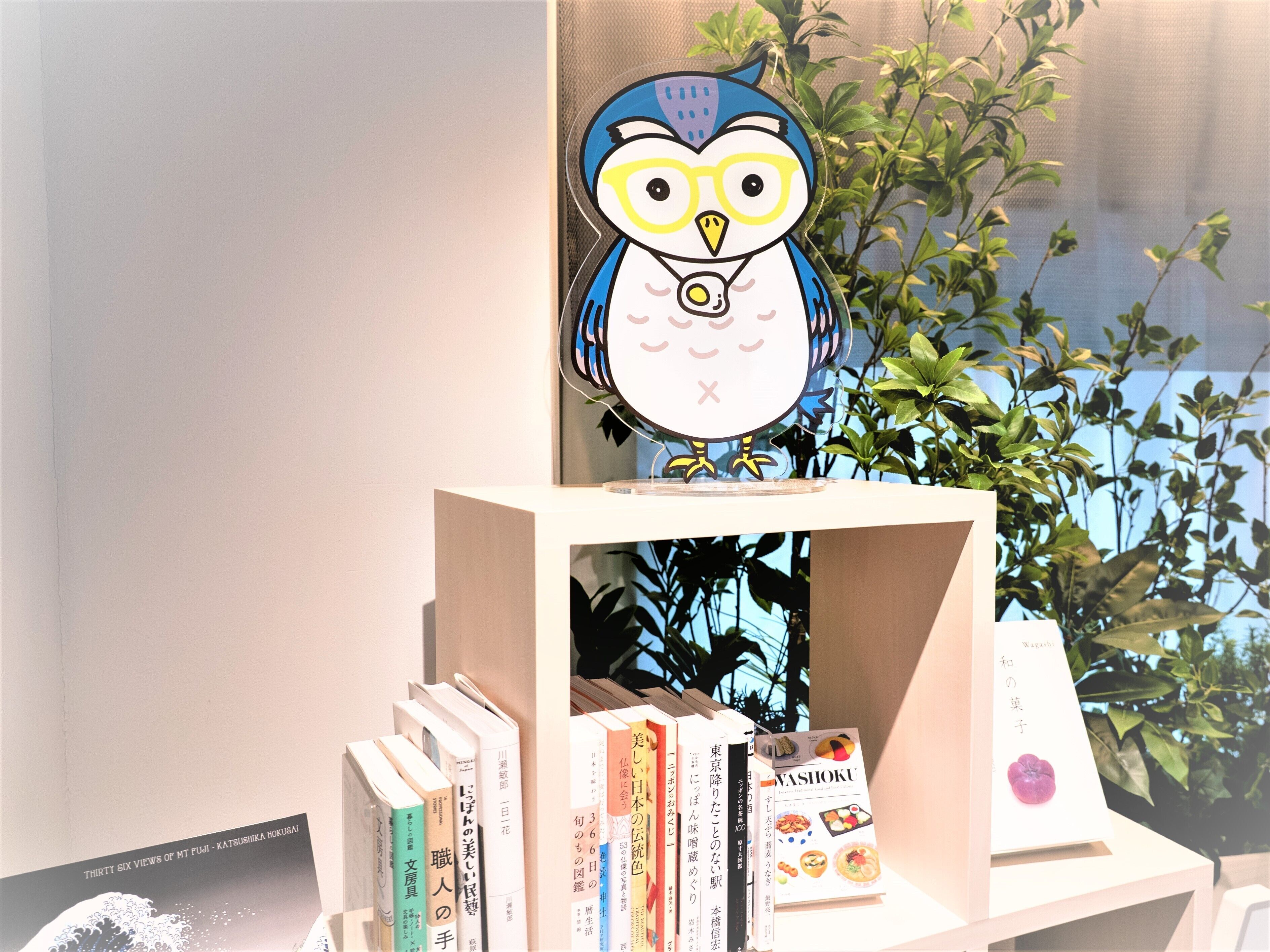 A bookshelf with books and a decorative owl figure.