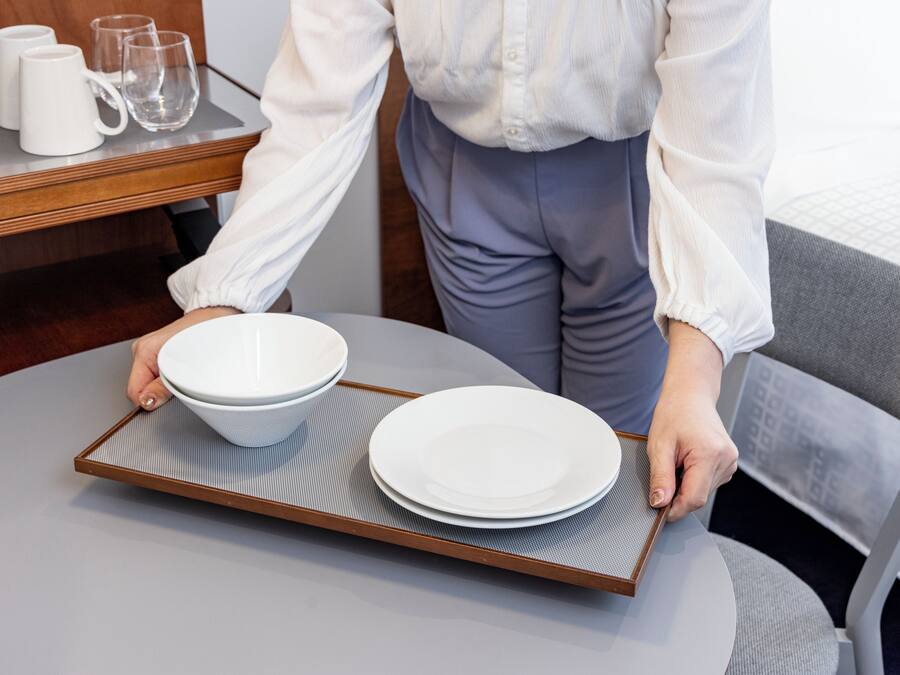 A person carrying a tray with two white bowls and a plate.