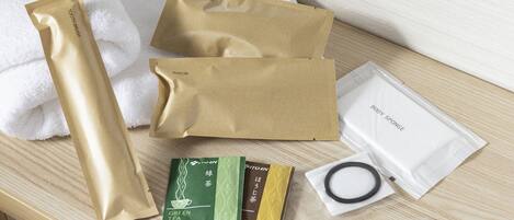 A wooden surface with various personal care items including a hair brush, razor, body sponge, tea bags, and cotton swabs.