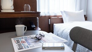 A hotel room with a bed, a bedside table with a newspaper, a coffee maker, and a glass of water. - Tokyu Stay Ikebukuro (Tokyo)