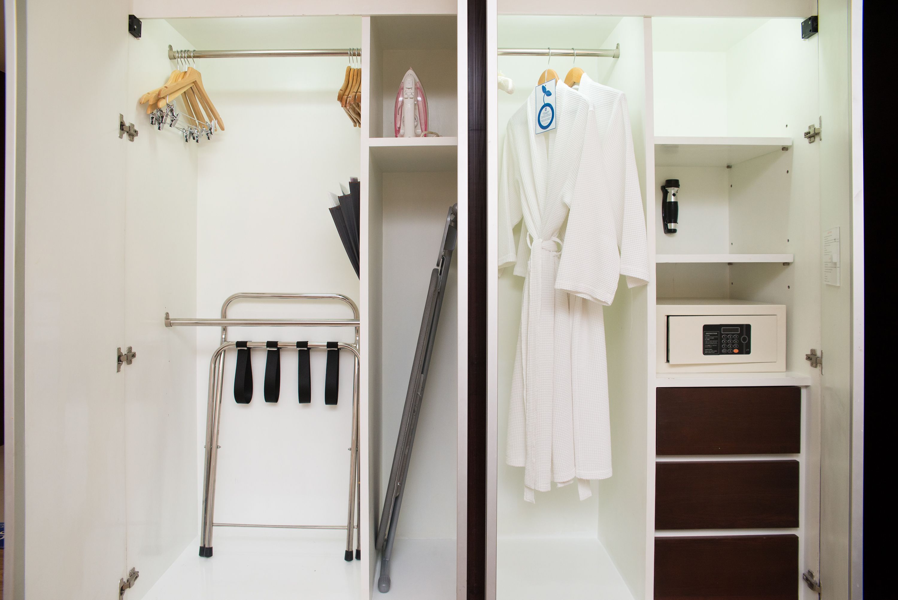 Un dressing avec un étendoir métallique, une planche à repasser et un four à micro-ondes posé sur une étagère.