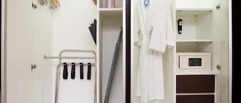 Un dressing avec un étendoir métallique, une planche à repasser et un four à micro-ondes posé sur une étagère.