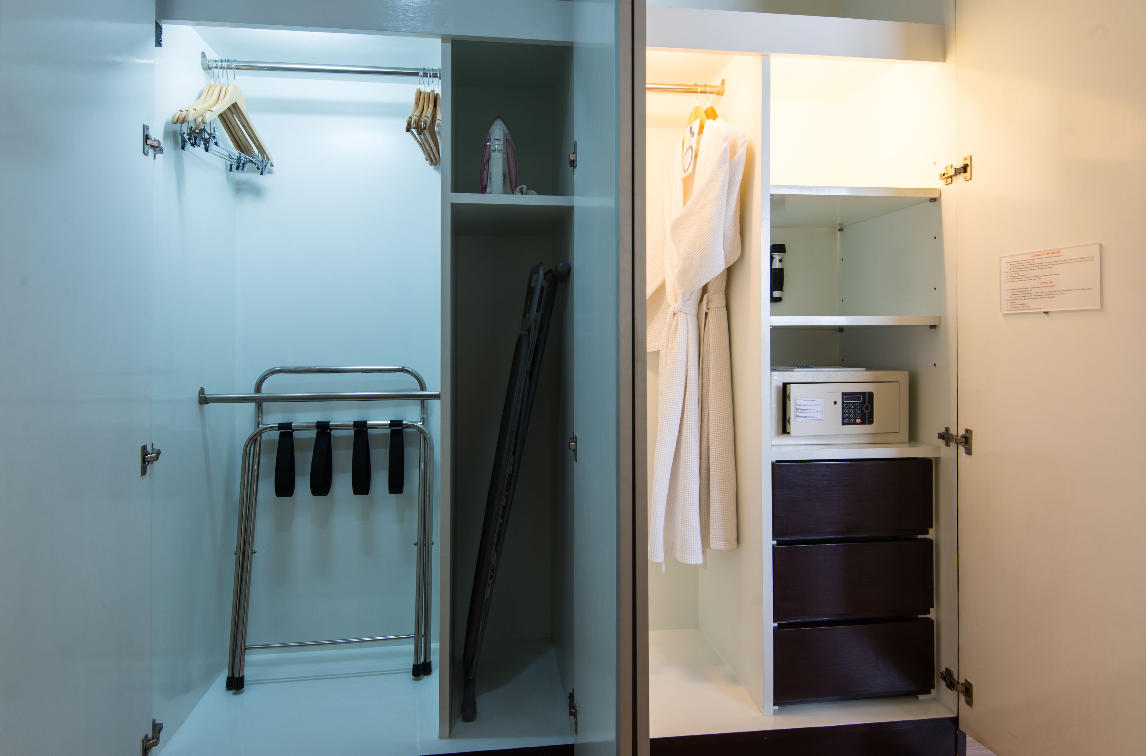 A hotel room with a walk-in closet containing a hanging rack, a coat rack, and a microwave.