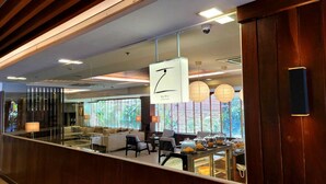 A modern cafe with a wooden interior, a large window with a view of greenery, and a sign indicating it is a cafe. - Lohas Residences Sukhumvit (Bangkok)