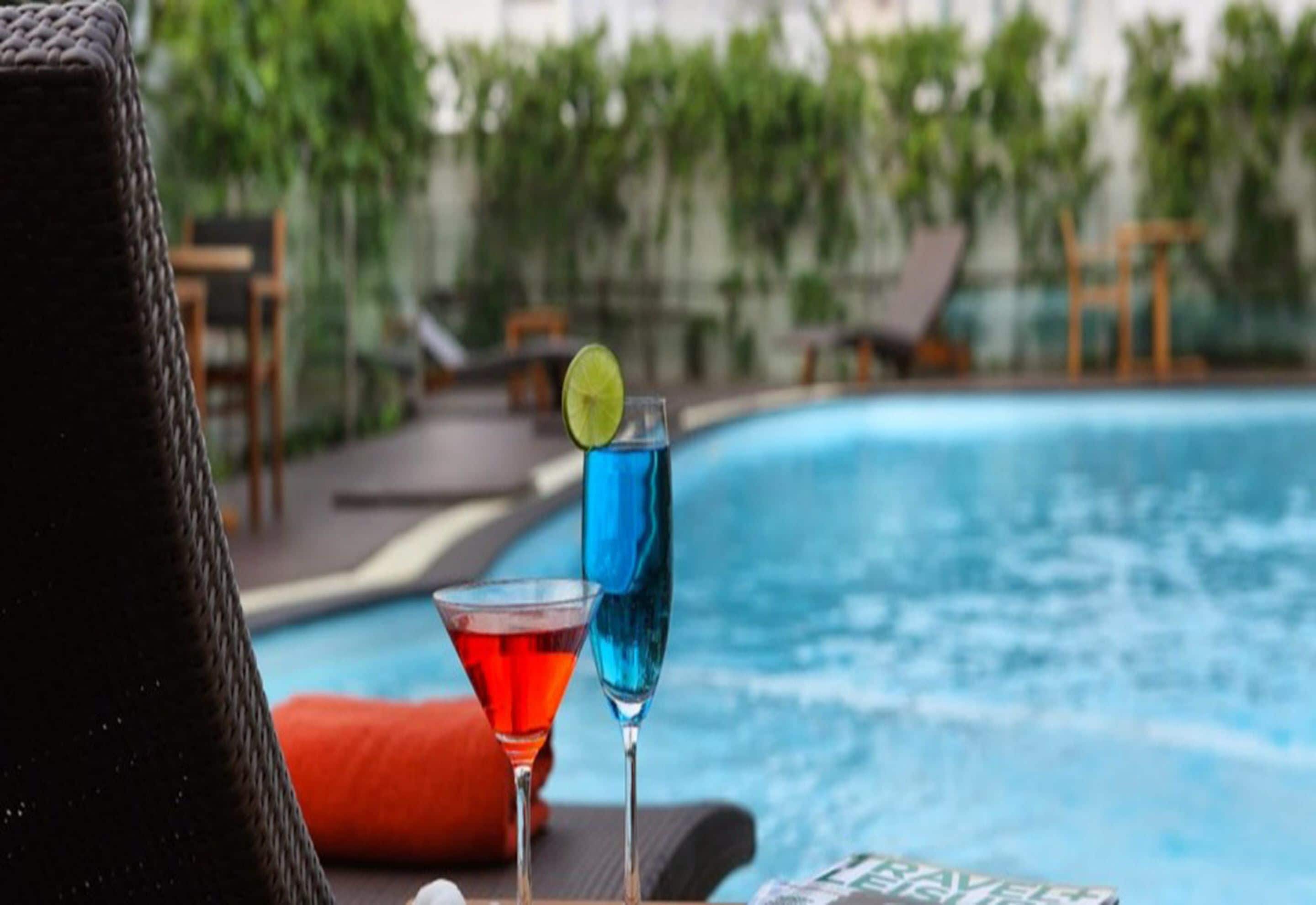 A poolside area with lounge chairs and a bar area with two cocktails.