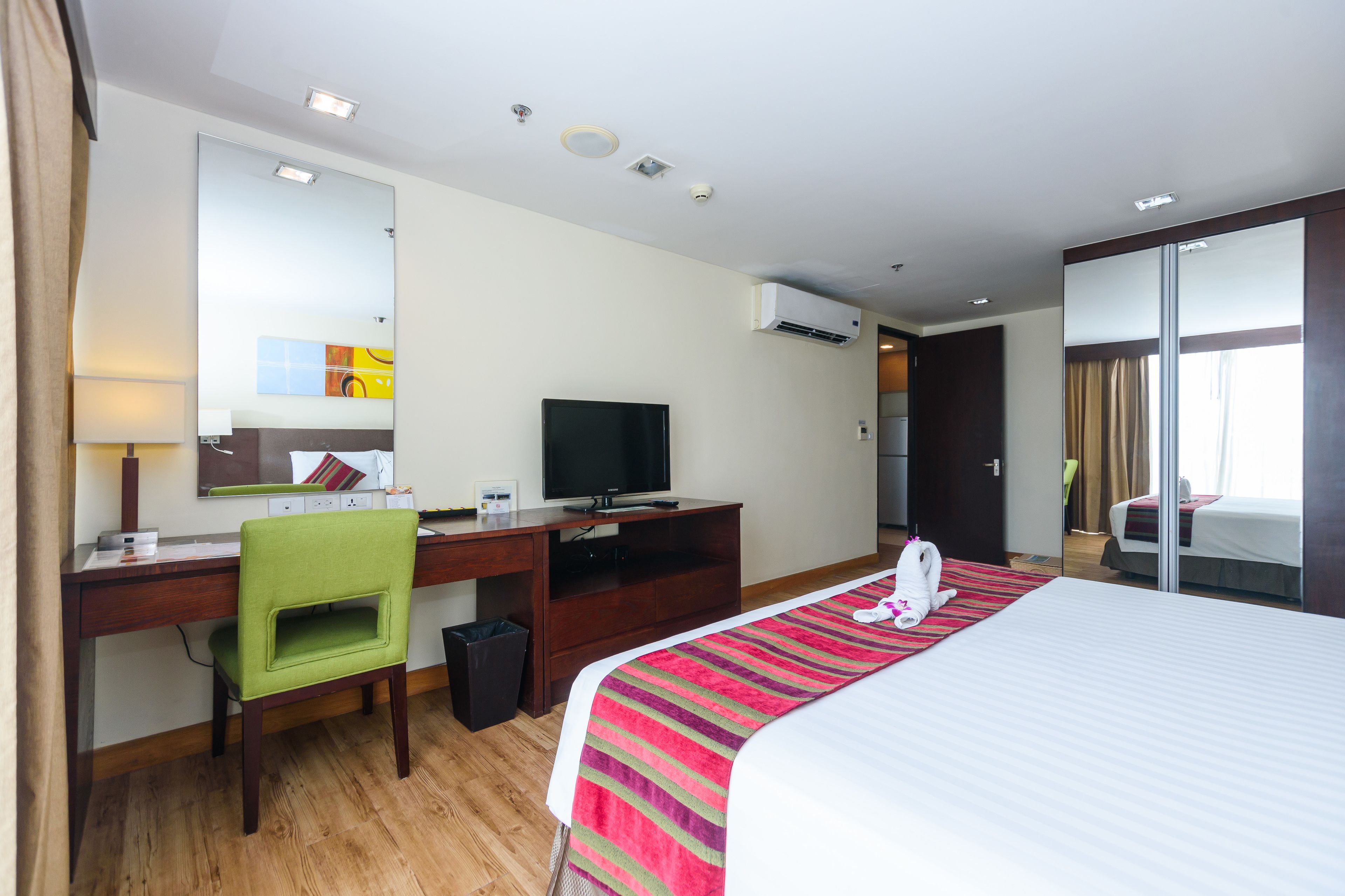 Une chambre d’hôtel équipée d’un lit, d’un bureau avec un ordinateur, d’une chaise, d’un téléviseur et d’un appareil de climatisation.