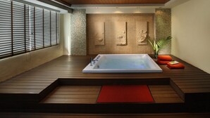 A modern spa room with a large hot tub, wooden flooring, and a red mat in the center. - Lohas Residences Sukhumvit (Bangkok)