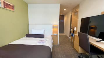 A hotel room with a bed, a desk, a chair, a TV, and a wall-mounted air conditioner.