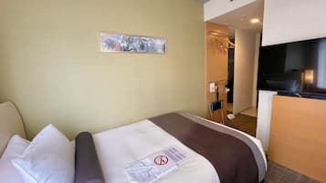 Une chambre d’hôtel avec un lit, des oreillers, une couverture, une télévision et un tableau au mur.