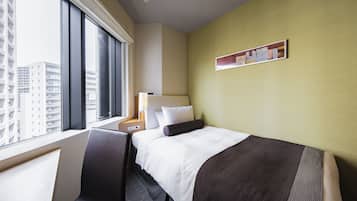 Una habitación de hotel con un ventanal grande, una cama con cabecero, una mesita de noche, una lámpara y una estantería fijada a la pared.