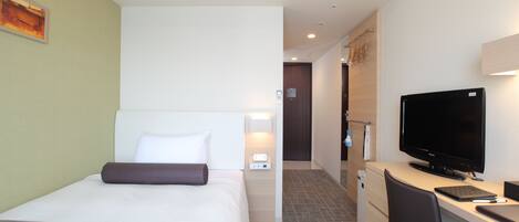 A hotel room with a bed, a desk, a television, and an air conditioning unit.
