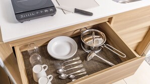 A drawer with kitchen utensils, including a pot strainer, spoons, forks, and a white plate. - Tokyu Stay Gotanda (Tokyo)
