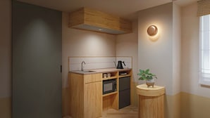A compact kitchen with wooden cabinetry, a built-in microwave, and a small round table with a potted plant. - Tokyu Stay Gotanda (Tokyo)