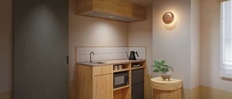 A compact kitchen with wooden cabinetry, a built-in microwave, and a small round table with a potted plant.