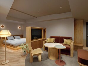 Un salon moderne avec un canapé, un téléviseur, une table basse et un fauteuil.