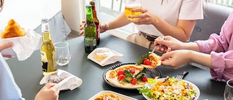 A group of people dining at a table with various dishes, drinks, and a bottle of wine.