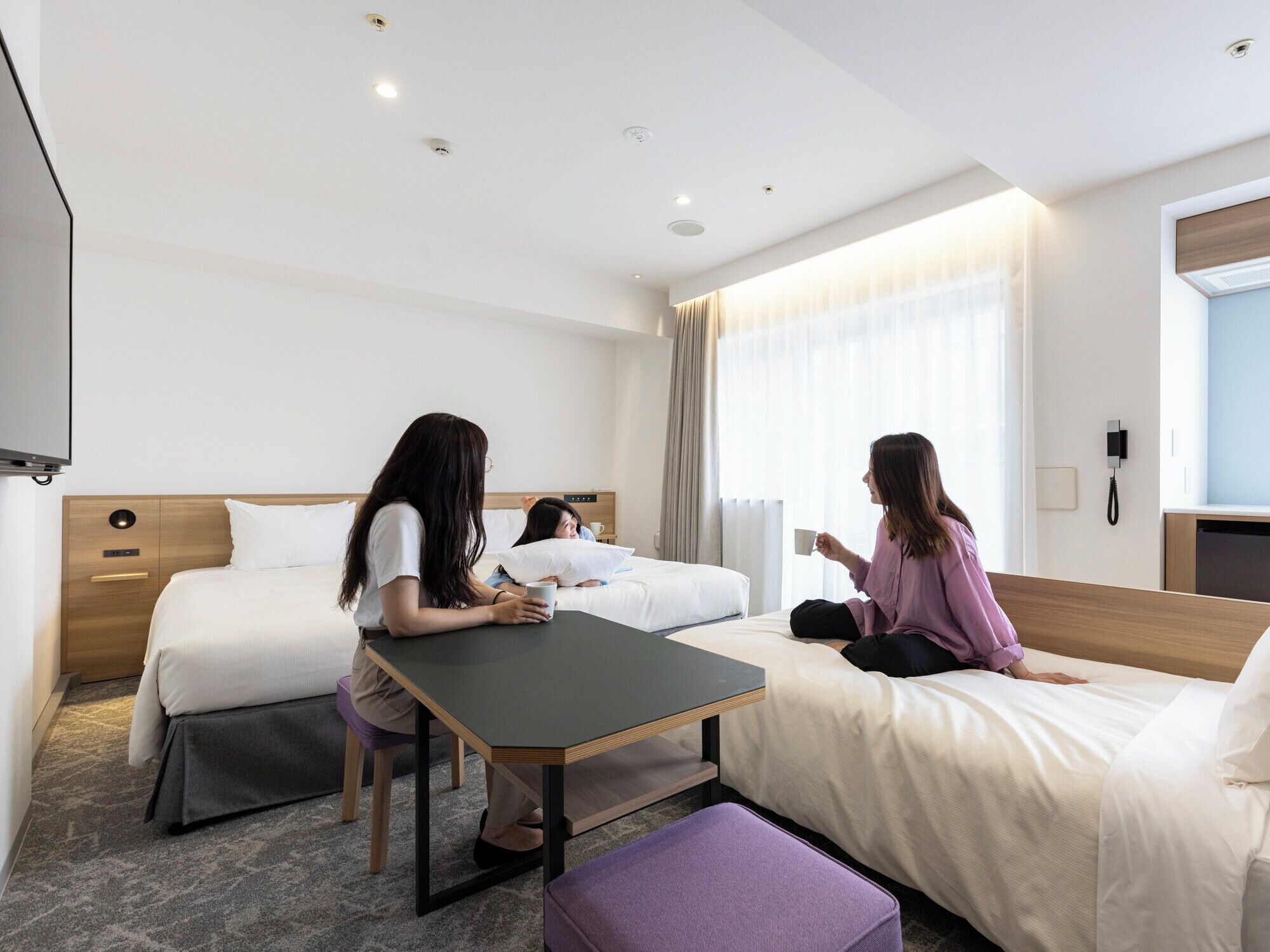 Habitación de hotel con dos camas, un escritorio y una televisión.