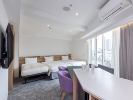 Una habitación de hotel con dos camas, un escritorio, sillas y un televisor.