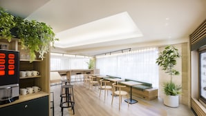 A modern cafe with a coffee machine, seating area, and plants. - Tokyu Stay Shibuya Shin-minamiguchi (Tokyo)