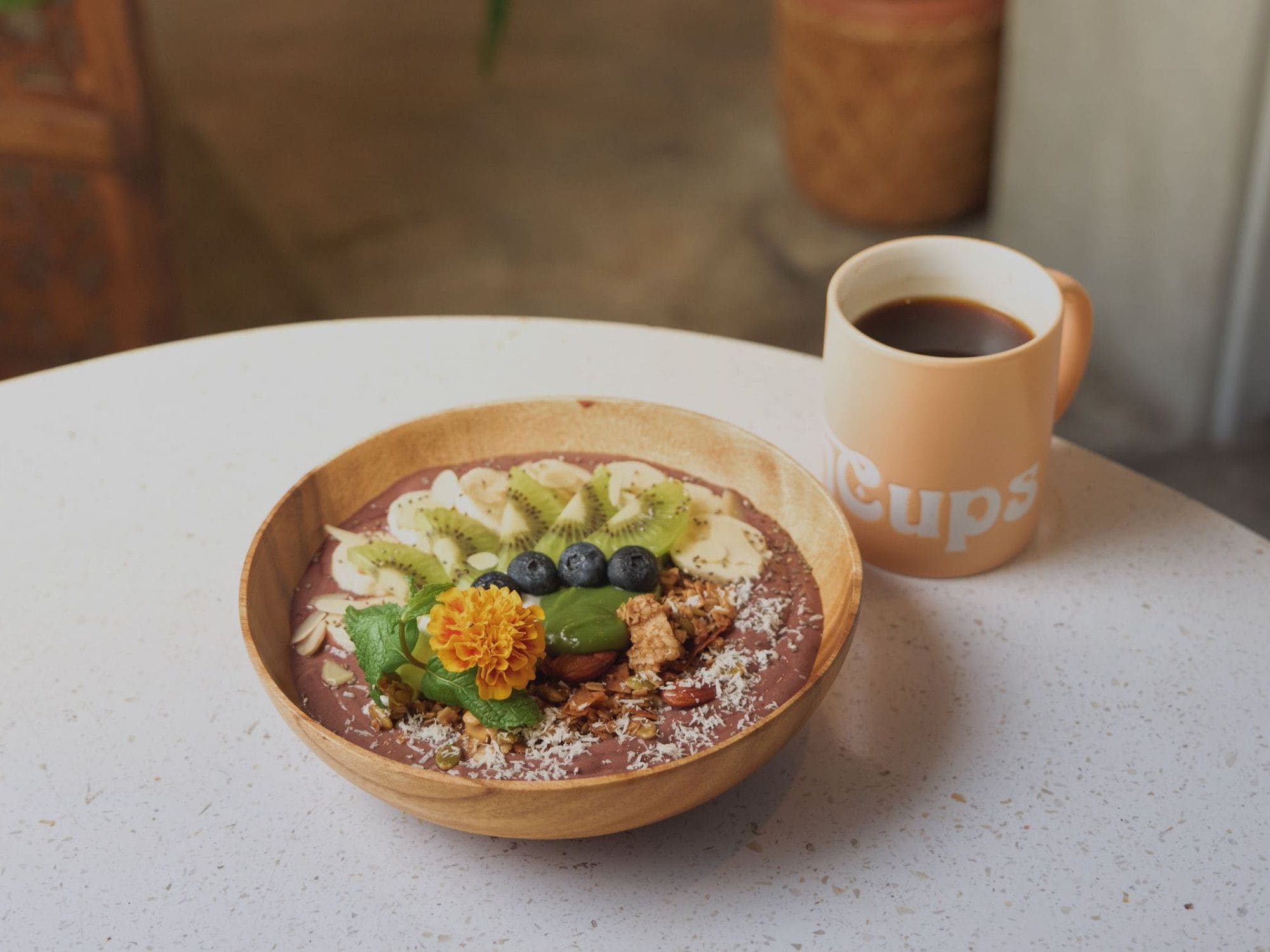 A bowl of smoothie with fruits and nuts on a table.