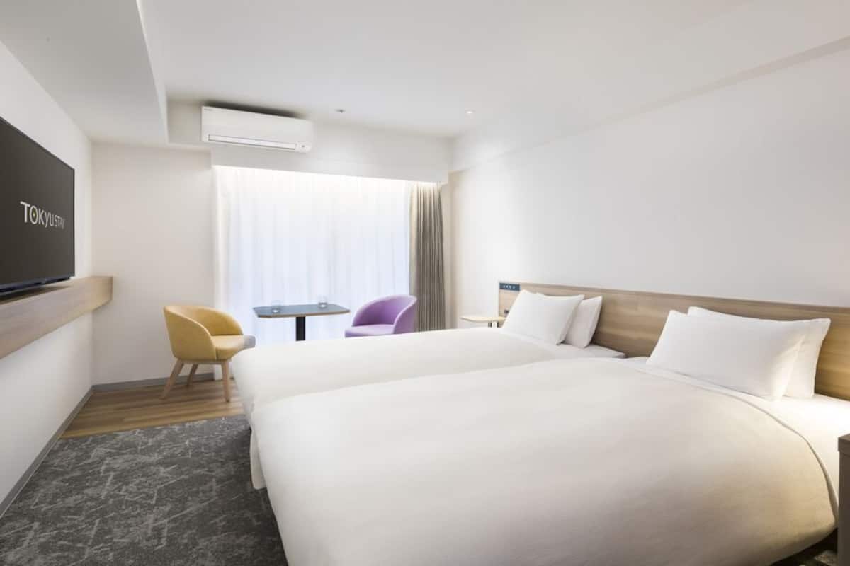 A hotel room with a large bed, a TV, a desk, and a chair.