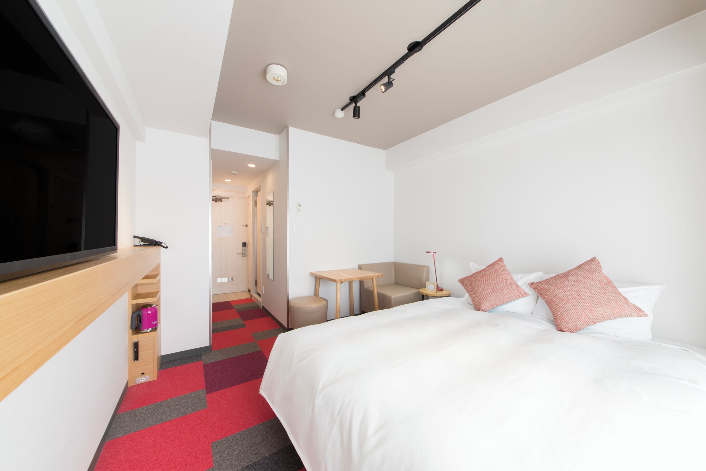 A hotel room with a bed, a desk, a chair, and a television.