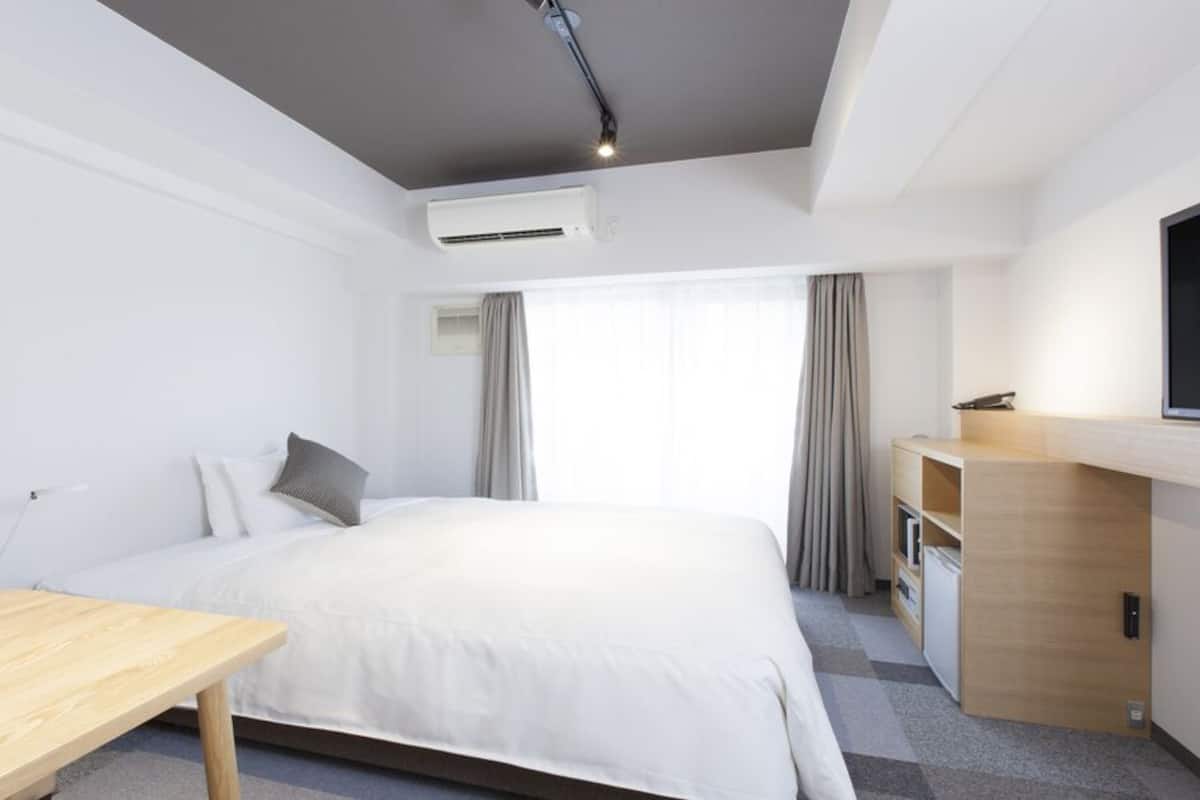 A hotel room with a bed, a desk, a TV, and a wardrobe.