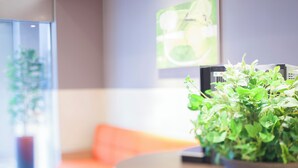 A modern interior with a round table, a potted plant, a sofa, and a wall-mounted artwork. - Tokyu Stay Yoga (Tokyo)