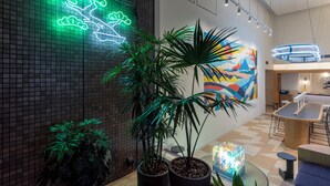 A modern interior with a neon tree sign, potted plants, a colorful mural, and a bar area. - Tokyu Stay Nihonbashi (Tokyo)