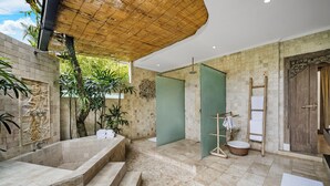 Ein Badezimmer mit einer großen Badewanne, einer Duschkabine und einer Holztür.