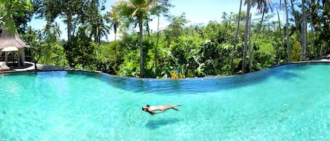 Een buitenzwembad, parasols bij het zwembad en ligstoelen