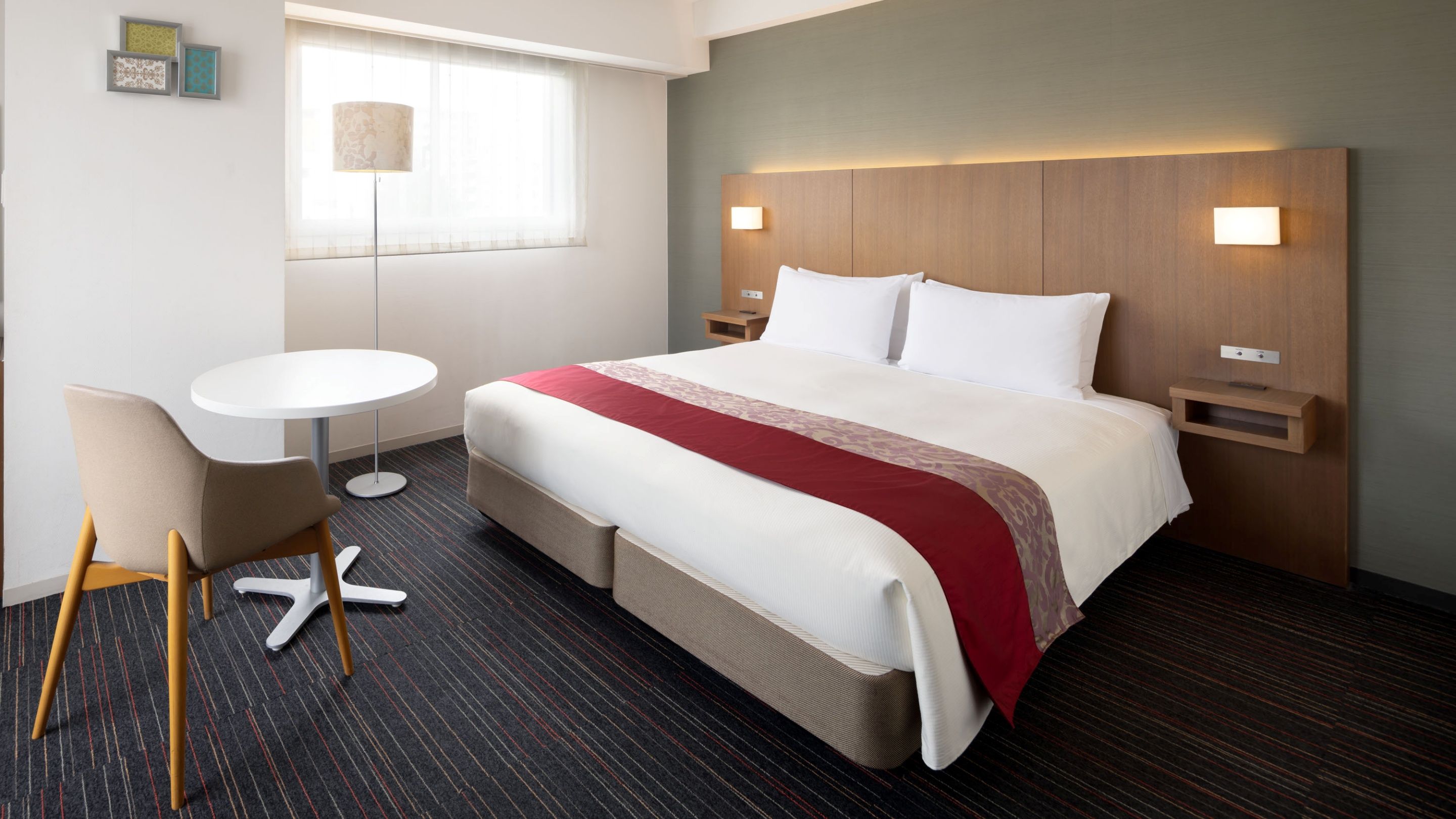 Una habitación de hotel con cama, mesitas de noche, un escritorio y una silla.